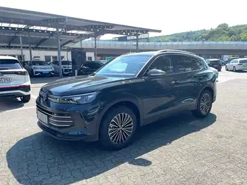 Das Bild zeigt ein schwarzes Fahrzeug, einen VW Tiguan, von der Seite aufgenommen. Es ist auf einem Parkplatz zu sehen.