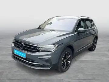 Das Bild zeigt einen grauen VW Tiguan aus der Frontalansicht. Es enthält markante Texteinblendungen.
