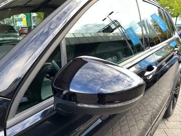 Das Bild zeigt die Seite eines schwarzen VW Tiguan, insbesondere den Außenspiegel.