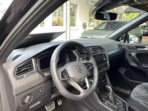 Innenaufnahme eines schwarzen VW Tiguan mit schwarzem Interieur, gezeigt wird das Lenkrad und das Armaturenbrett.