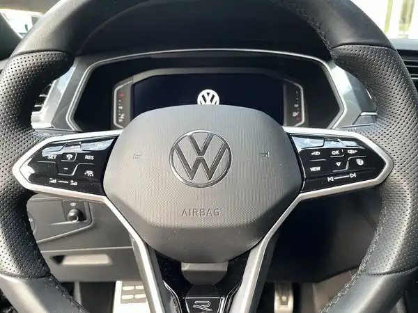 Innenaufnahme des Fahrzeugs, zeigt das Lenkrad und das Cockpit des VW Tiguan in schwarzer Farbe.