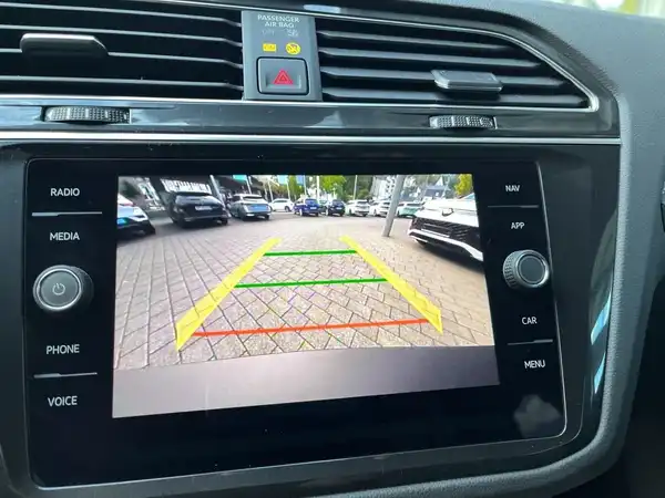 Das Bild zeigt den Innenraum des Fahrzeugs, spezifisch den Bildschirm des Navigationssystems mit einer Rückfahrkameraansicht. Die Interieurfarbe ist schwarz.