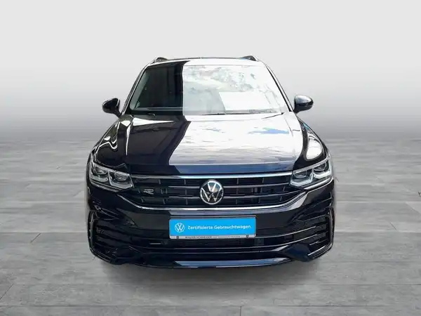 Das Bild zeigt einen schwarzen VW Tiguan aus der Frontalansicht mit einem Händlerinformationsbanner.