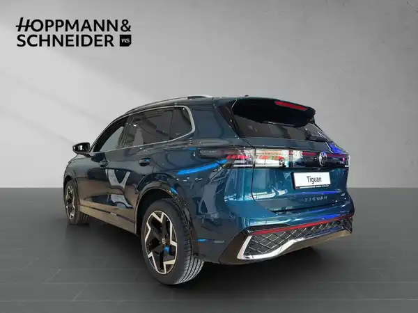 Das Bild zeigt einen blauen VW Tiguan von hinten, aufgenommen in einem Studio mit dem Händlermarkenzeichen HOPPMANN & SCHNEIDER im Bild.