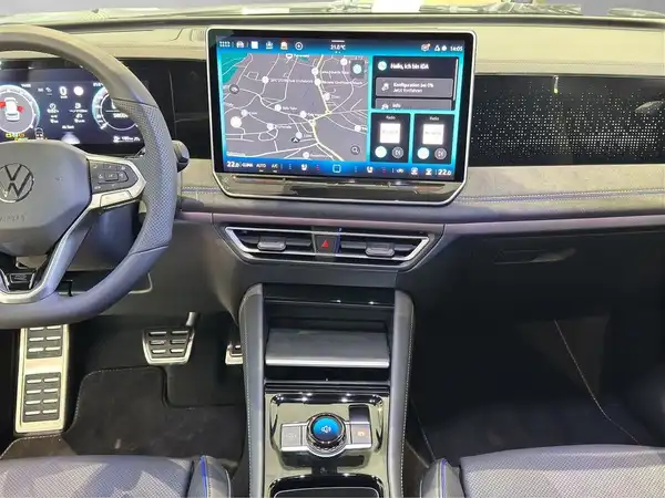 Das Bild zeigt den Innenraum eines VW Tiguan mit schwarzem Interieur und einem großen Touchscreen, der Navigationsinformationen anzeigt.
