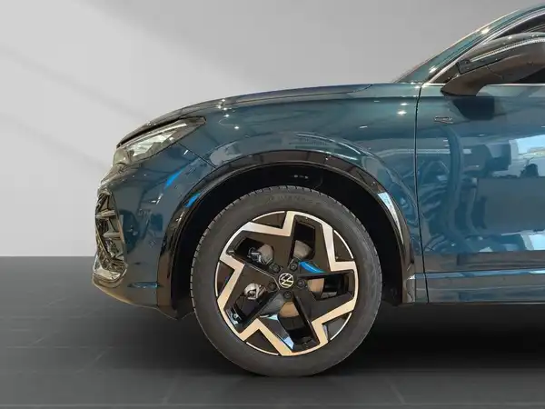 Das Bild zeigt die Seitenansicht eines blauen VW Tiguan mit einem auffälligen Felgendesign.