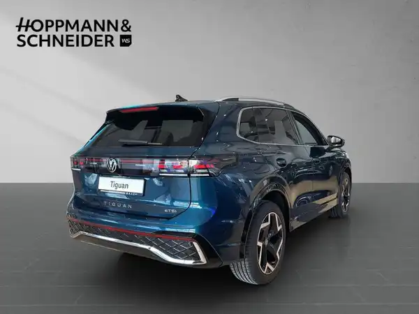 Das Bild zeigt einen blauen VW Tiguan von hinten. Im Hintergrund ist das Händlerlogo "HOPPMANN & SCHNEIDER" zu sehen.