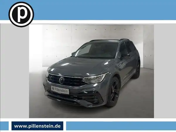 Das Bild zeigt einen grauen VW Tiguan aus Frontalansicht. Es ist ein Fahrzeugbild, das das Händlerlogo enthält und markante Texteinblendungen aufzeigt.