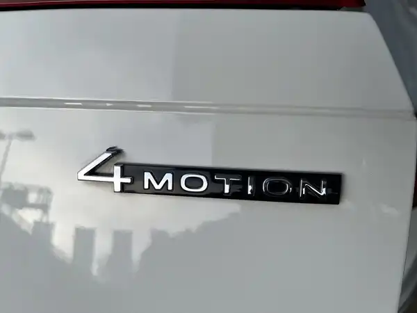 Das Bild zeigt das Heck eines VW Tiguan Allspace in Weiß, mit der Beschriftung '4MOTION'.