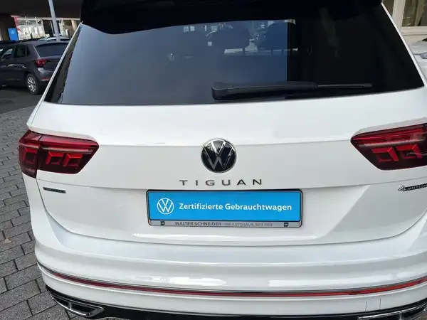 Das Bild zeigt die Rückansicht eines weißen VW Tiguan. Im Bild ist das Händlerlogo sichtbar, sowie eine markante Texteinblendung mit der Aufschrift "Zertifizierte Gebrauchtwagen".