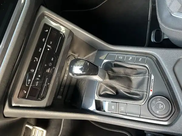 Dieses Bild zeigt das Innere eines Fahrzeugs, insbesondere den Schalthebel und das Infotainment-System. Das Interieur ist schwarz.
