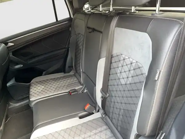 Das Bild zeigt den Innenraum eines VW Tiguan Allspace, mit einem Fokus auf den Rücksitz, der in schwarz mit grauen Akzenten gestaltet ist.