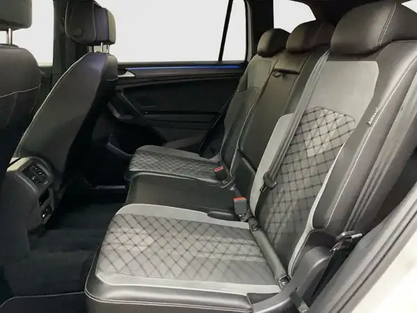 Auf dem Bild ist der Innenraum eines Fahrzeugs zu sehen, genauer gesagt die Rückbank des VW Tiguan Allspace. Die Sitze sind schwarz mit gestepptem Muster.