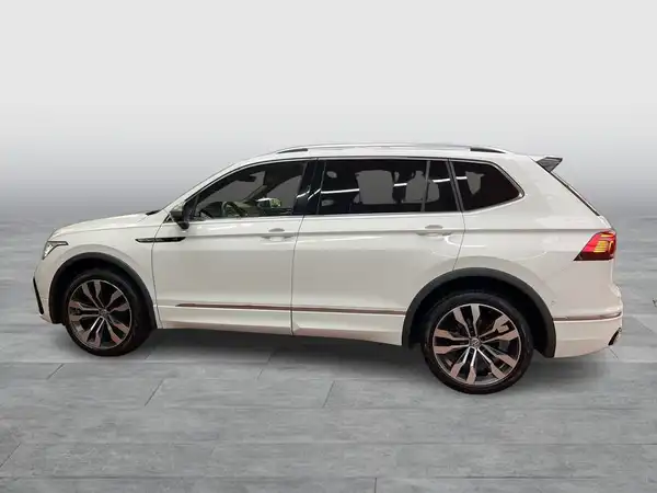Das Bild zeigt einen VW Tiguan Allspace von der Seite in weißer Farbe.