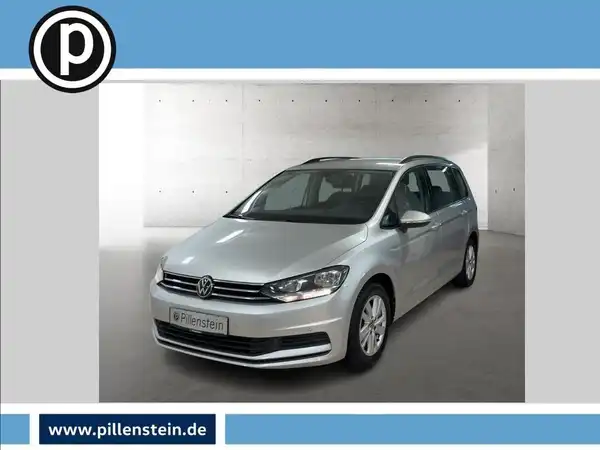 Das Bild zeigt einen silbernen VW Touran von vorne, mit einem kleinen Händlerlogo in der oberen linken Ecke und auffälligen Texteinblendungen.