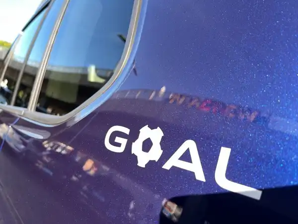 Das Bild zeigt die Seite eines lila VW Touran mit dem markanten Aufkleber "GOAL".