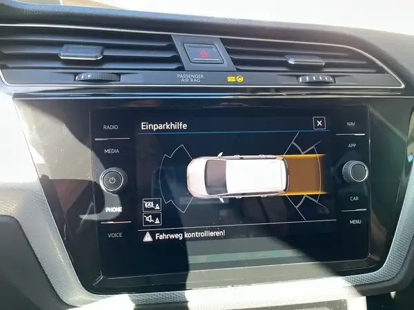 Eine Innenaufnahme des Fahrzeugs, die das Navigations- und Informationssystem zeigt, auf dem die Einparkhilfe angezeigt wird. Die Interieurfarbe ist schwarz.