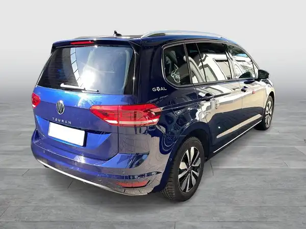 Das Bild zeigt einen blauen VW Touran von hinten, wobei das Fahrzeug klar im Vordergrund steht.