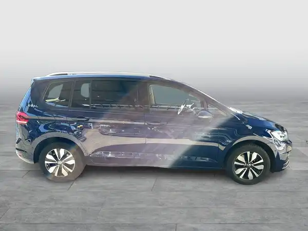 Das Bild zeigt einen VW Touran in blauer Farbe, aufgenommen von der Seite.