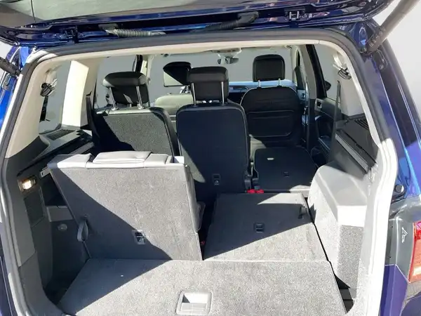 Innenaufnahme des Fahrzeugs mit einem blauen Außenlack und schwarzem Interieur. Das Bild zeigt den Kofferraum und die umgeklappten Rücksitze.