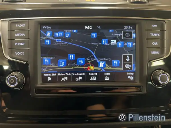 Das Bild zeigt das Innenleben eines VW Touran mit einem Navigationsgerät. Der Bildschirm zeigt eine Karte und verschiedene Optionen an. Die Farbe des Interieurs ist schwarz und es ist ein Händlersignet zu sehen.