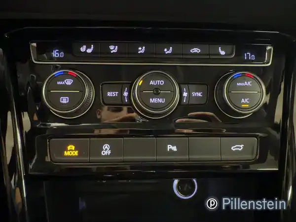 Bild zeigt eine Innenaufnahme des VW Touran mit Bedienelementen der Klimaanlage und Infotainment, in schwarzer Farbe. Händlerlogo ist sichtbar. Es sind weitere Texteinblendungen vorhanden.