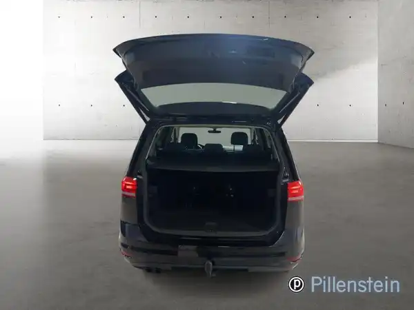 Das Bild zeigt den Kofferraum eines schwarzen VW Touran von hinten. Der Kofferraum ist geöffnet.