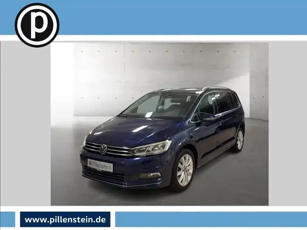 Das Bild zeigt einen blauen VW Touran von vorne. Es enthält das Händlerinformationslogo und deutliche Texteinblendungen.