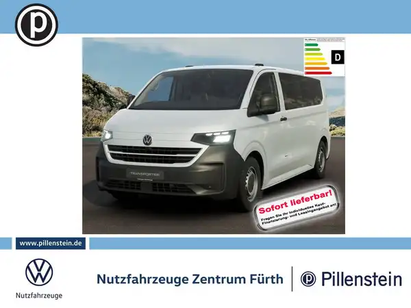 Das Bild zeigt einen weißen VW Transporter aus der Frontalansicht. Es handelt sich um eine Anzeige mit Händlerlogo und einer Texteinblendung, die besagt, dass das Fahrzeug sofort lieferbar ist.