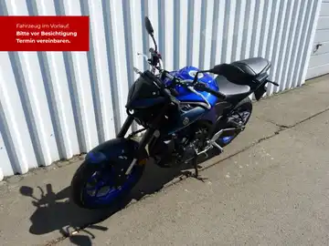 Das Bild zeigt eine YAMAHA MT-03 von der Seite in blau. Es enthält textliche Informationen über die Fahrzeugbesichtigung.