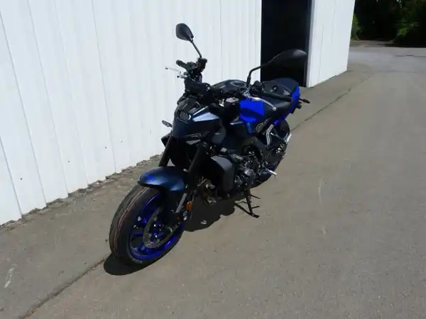 Das Bild zeigt eine YAMAHA MT-09 aus der Seitenansicht, in blauer Farbe, auf einem Asphaltweg.
