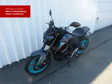 Das Bild zeigt eine YAMAHA MT-125 von der Seite. Das Fahrzeug ist schwarz mit blauen Akzenten. Es gibt markante Texteinblendungen, die auf eine Fahrzeugbesichtigung hinweisen.