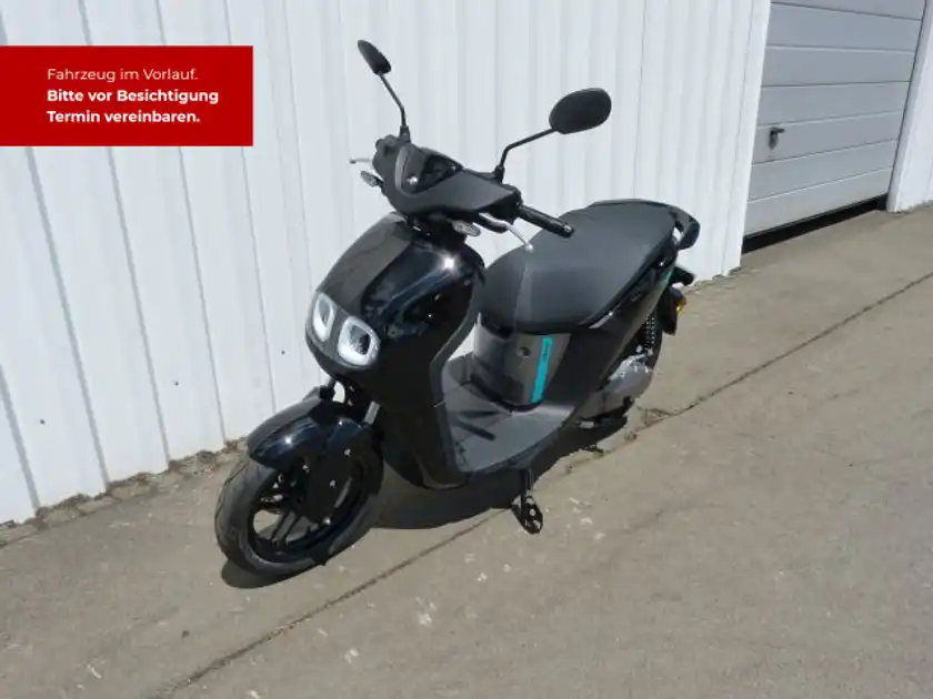 Ein Bild von einem schwarzen Yamaha NEO's Scooter, von der Seite aufgenommen. Es enthält markante Texteinblendungen, die auf die Fahrzeugbesichtigung hinweisen.