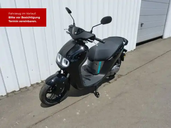 Ein Bild von einem schwarzen Yamaha NEO's Scooter, von der Seite aufgenommen. Es enthält markante Texteinblendungen, die auf die Fahrzeugbesichtigung hinweisen.