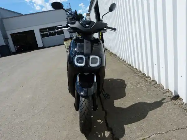 Das Bild zeigt einen schwarzen YAMAHA NEO's aus der Frontalansicht, aufgenommen in einer Außenumgebung.