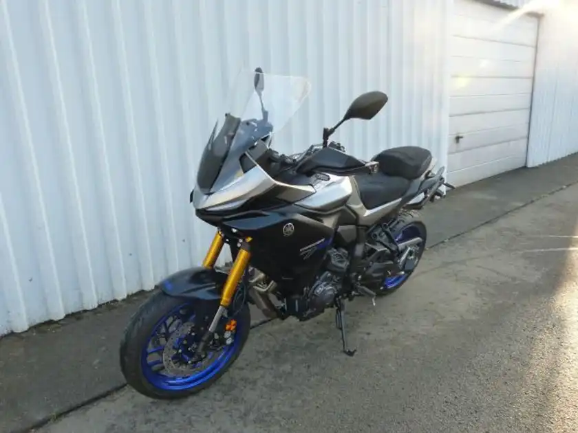 Das Bild zeigt eine silberne Yamaha Tracer von der Seite, aufgenommen an einer Wand.