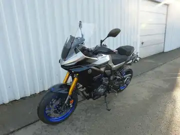 Das Bild zeigt eine silberne Yamaha Tracer von der Seite, aufgenommen an einer Wand.