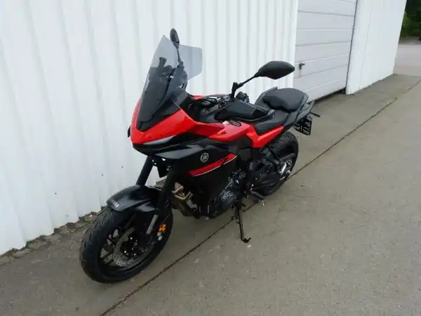 Das Bild zeigt ein rot-schwarzes Motorrad, aufgenommen von der Seite.