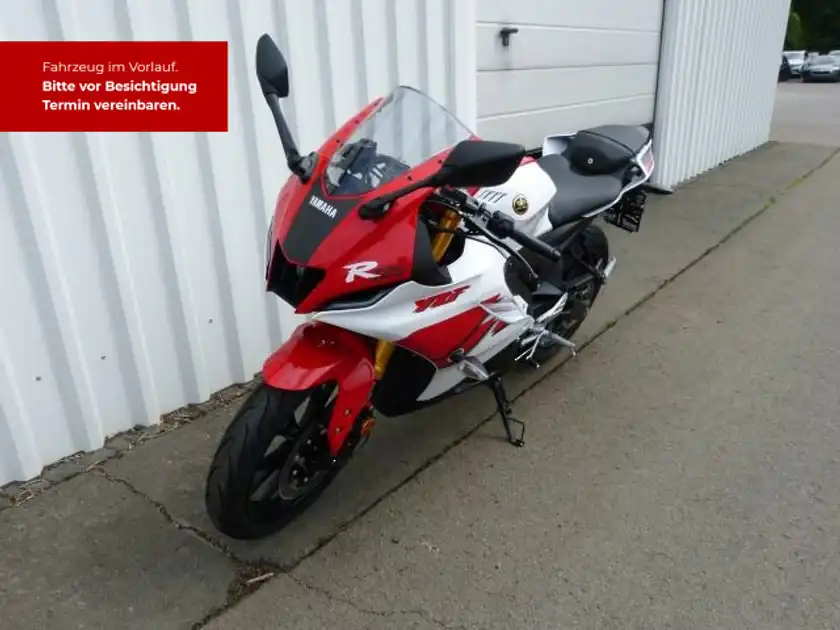 Das Bild zeigt eine YAMAHA YZF-R125 von der Seite in den Farben rot und weiß. Es gibt eine markante Texteinblendung in rot, die darauf hinweist, dass das Fahrzeug im Voraus verfügbar ist und um einen Besichtigungstermin bittet.